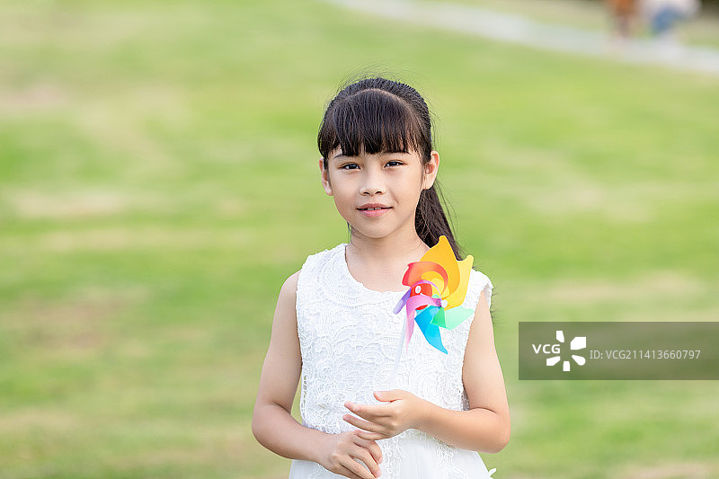 一个中国小女孩在公园里玩风车图片素材
