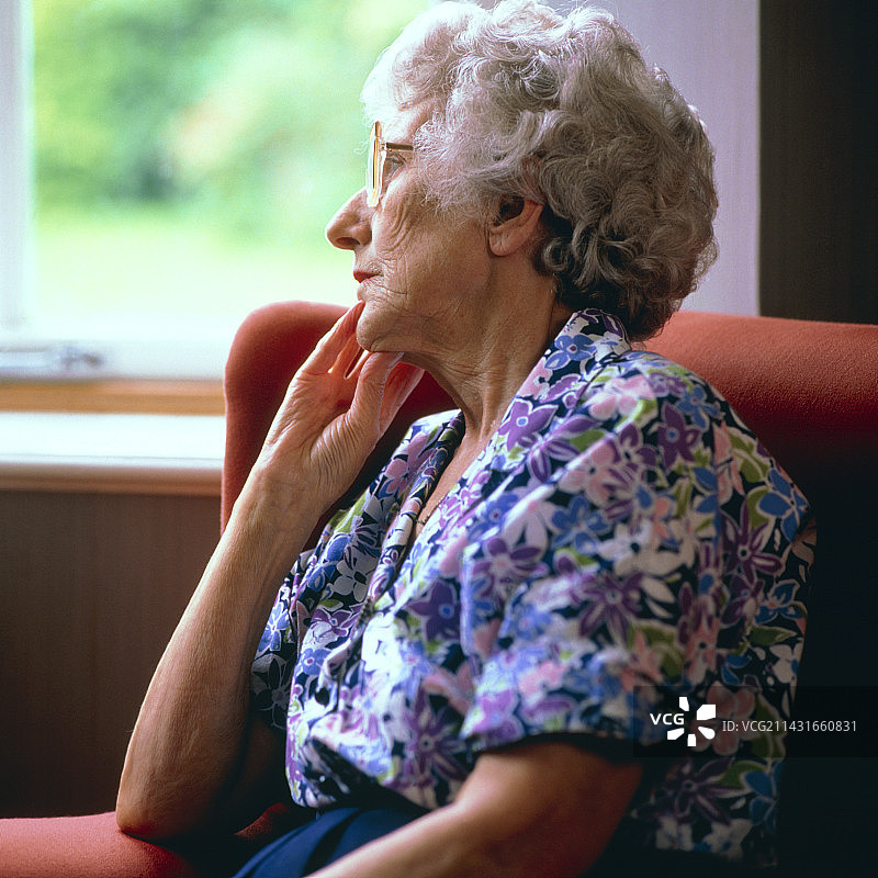 孤独:一位老妇人凝视着窗外图片素材
