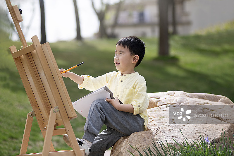 可爱的小男孩在户外画画图片素材