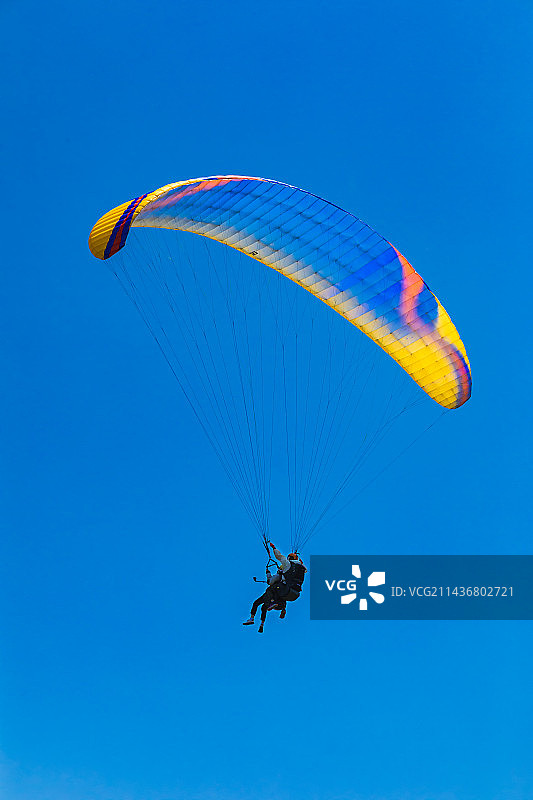 在晴朗的蓝天下滑翔伞的低角度视角图片素材