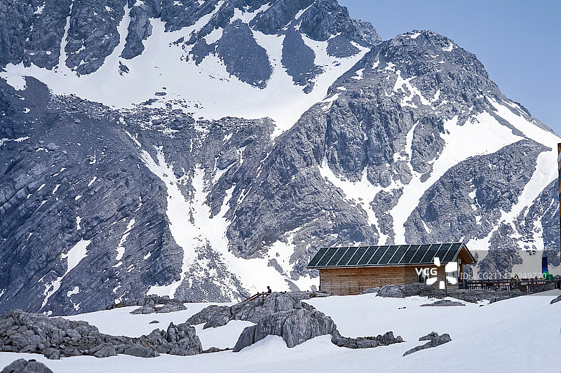白雪皑皑的群山在天空中的全景与玉龙雪山下的房屋图片素材