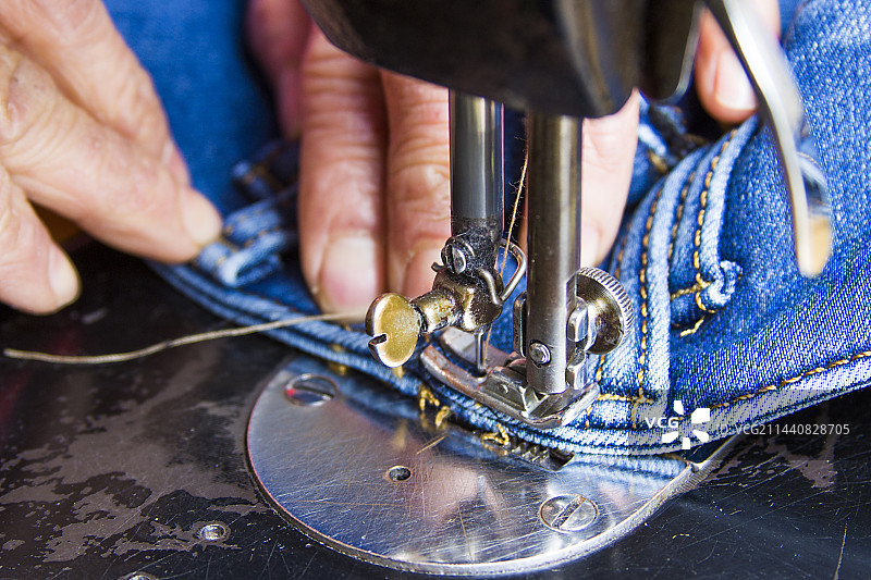 人工用老式缝纫机修补牛仔裤图片素材