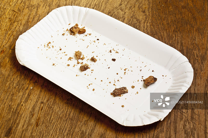 一个空的纸板蛋糕盘，木头表面有一些面包屑图片素材