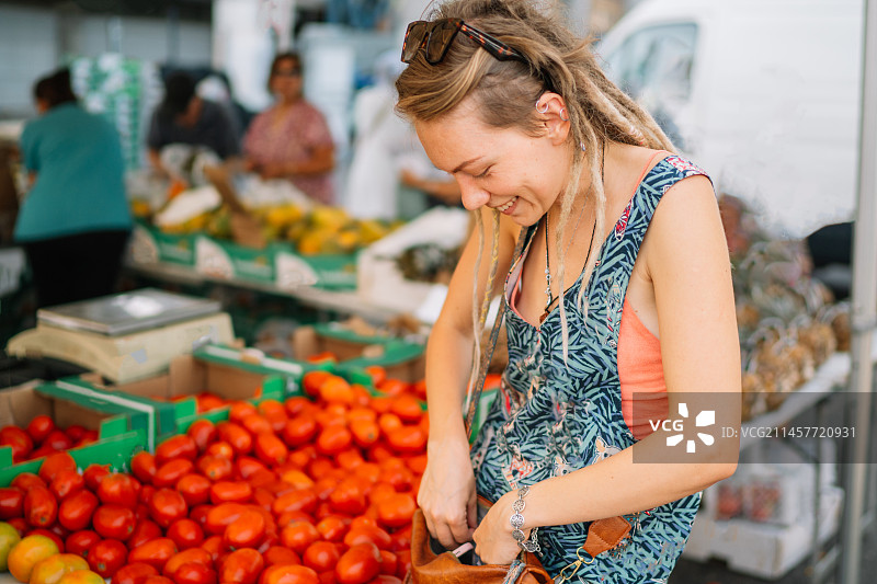 快乐的年轻女子在市场上买新鲜蔬菜图片素材