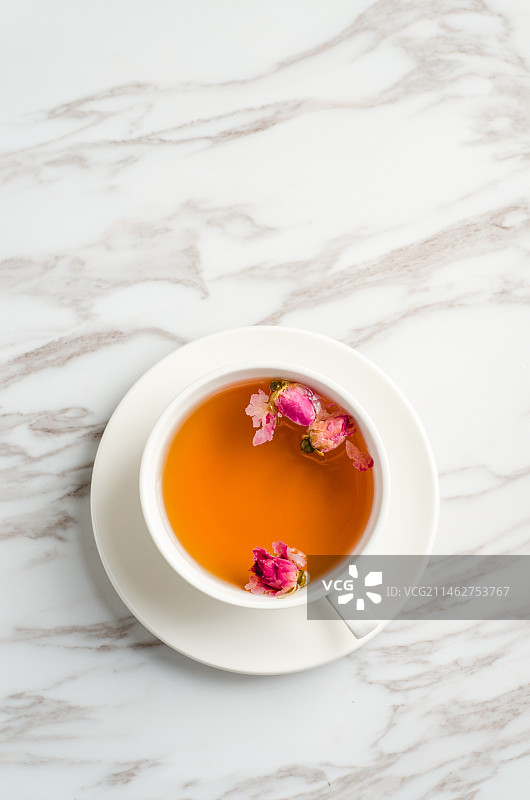 白色茶杯里泡好的玫瑰花茶和干玫瑰花图片素材