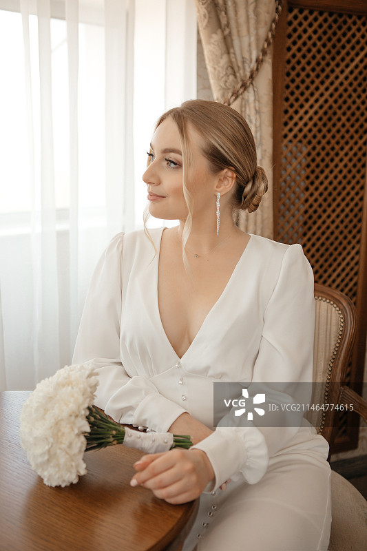 俄罗斯，新娘手持一束鲜花坐在椅子上图片素材