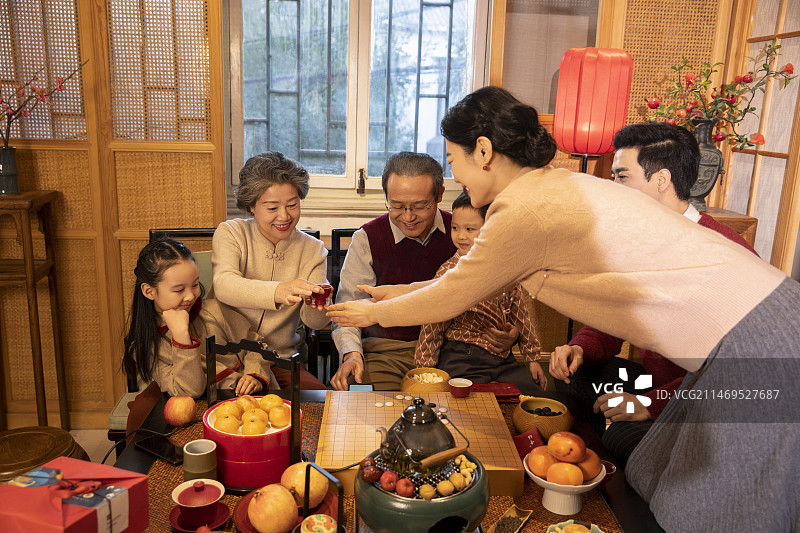 东方家庭过年：幸福一家人在客厅喝茶、玩围棋、聊天嬉戏图片素材