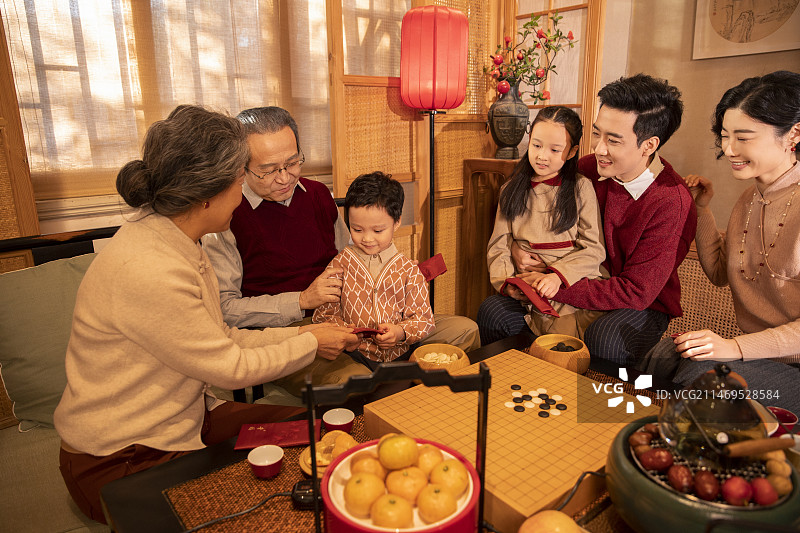 东方家庭过年：幸福一家人在客厅拜年、送压岁红包图片素材