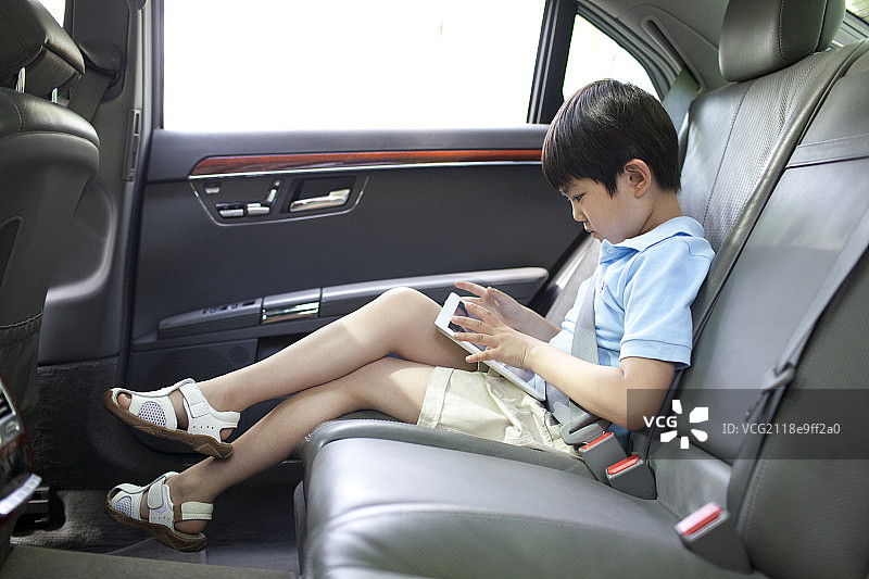 小男孩坐在车上玩平板电脑图片素材