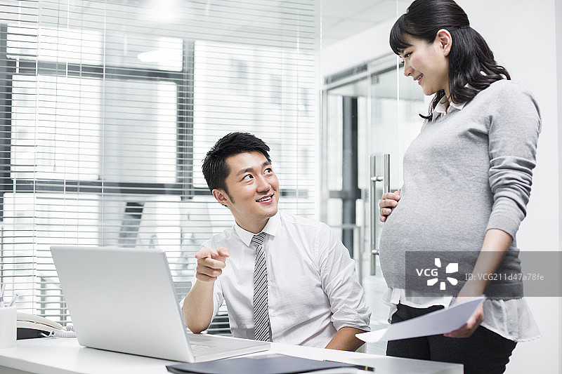 怀孕的商务女士和同事一起工作图片素材