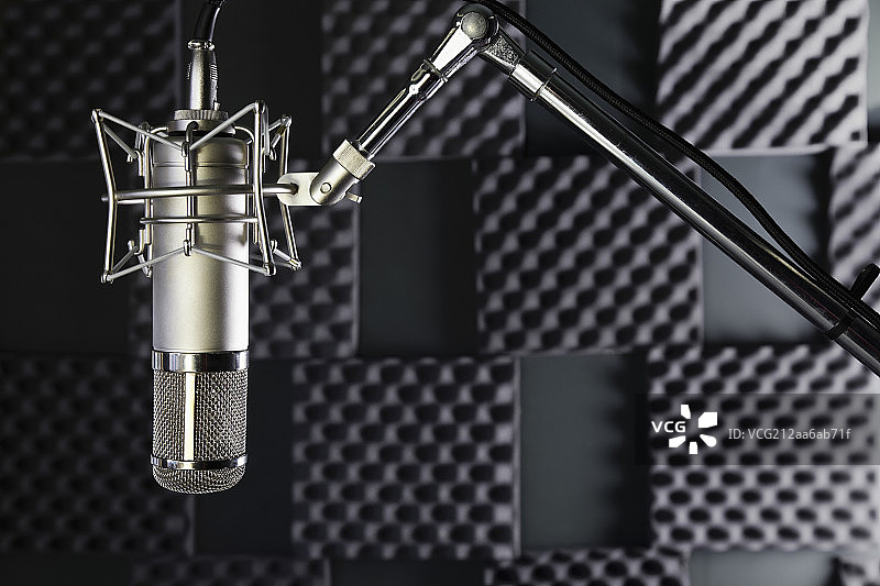 A professional microphone in a home recording studio with sound proof walls图片素材