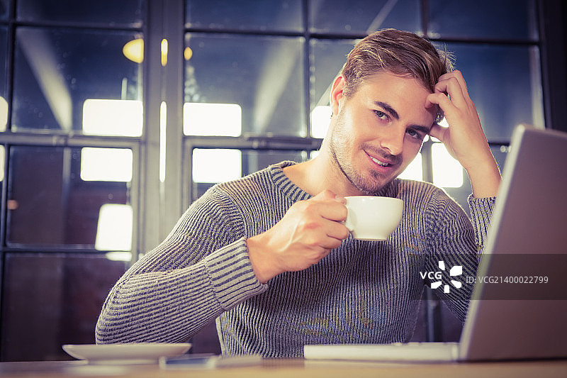 肖像英俊的男子微笑和喝咖啡在咖啡店图片素材