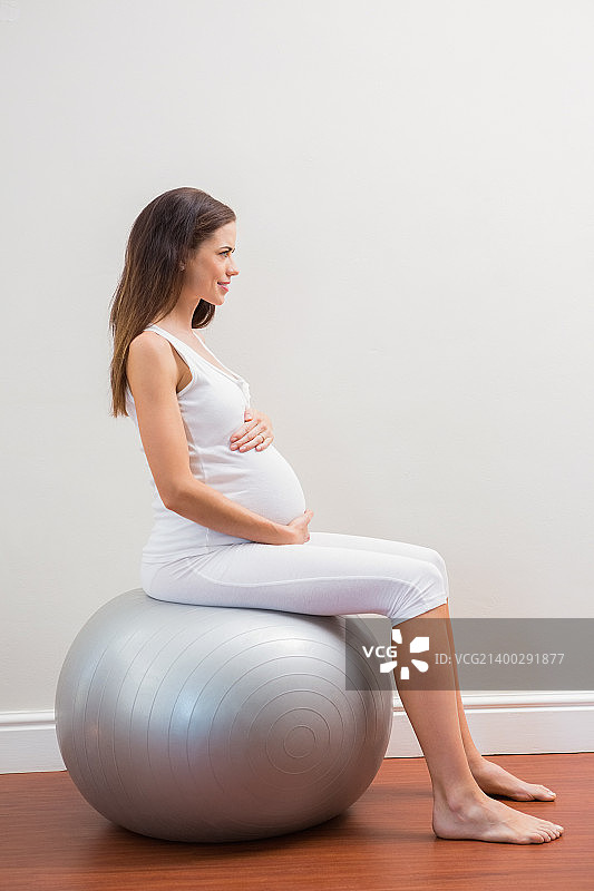 快乐怀孕坐在健身球上的房间图片素材