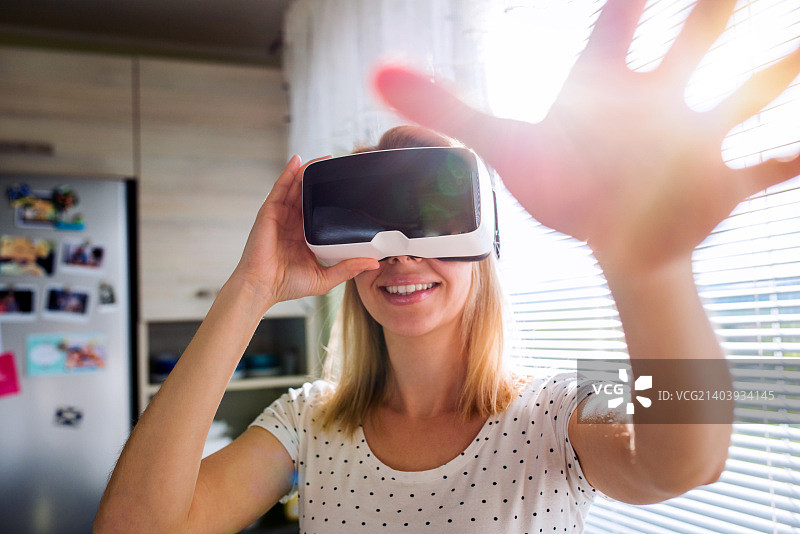一个戴着虚拟现实眼镜的女人站在厨房里图片素材