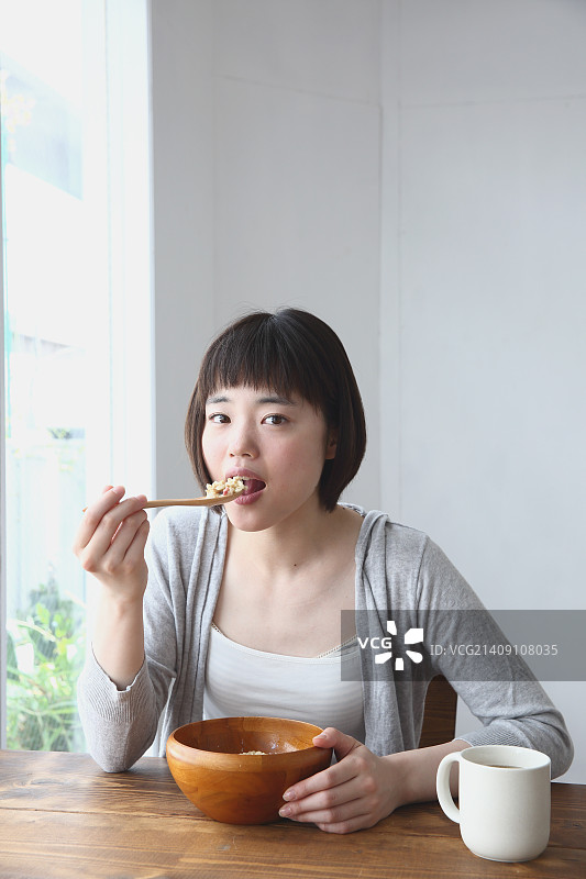 年轻的日本妇女在通风的房间里吃早餐图片素材