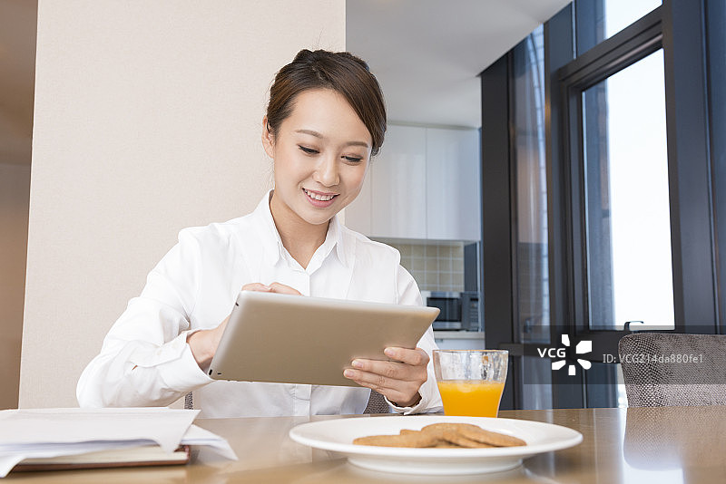 Young woman using tablet at breakfast图片素材