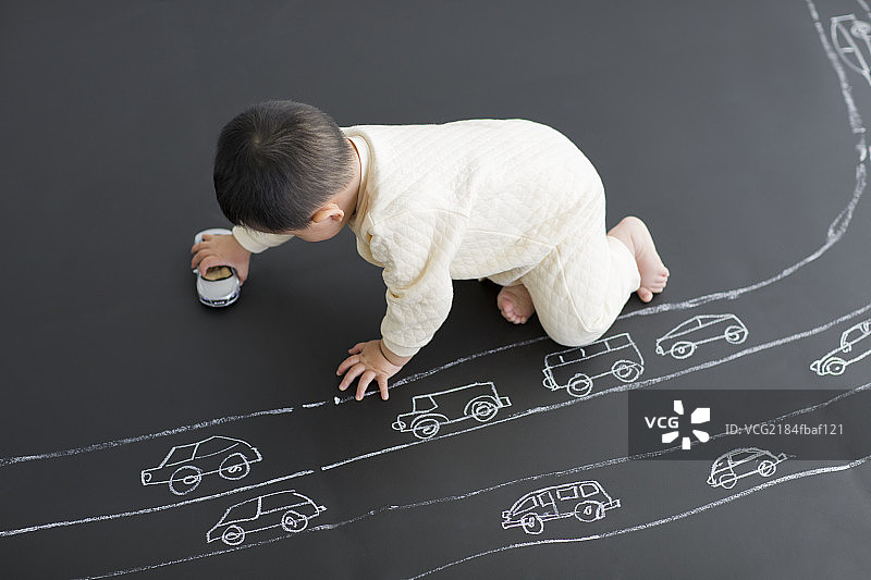 可爱的宝宝在画板上玩小汽车图片素材
