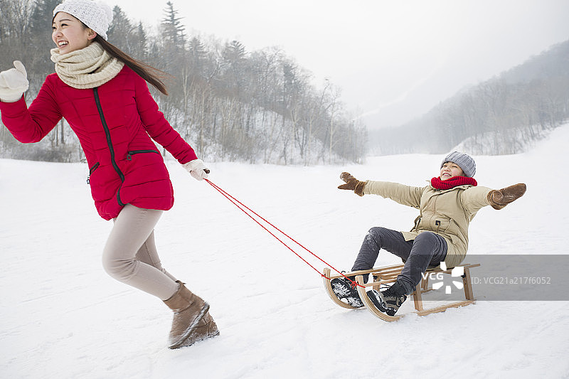母子俩在雪地上玩雪橇图片素材