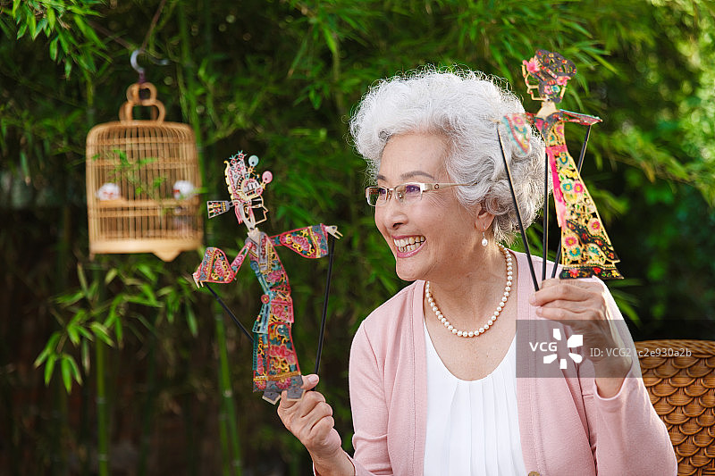 一个老年女人拿着皮影偶图片素材