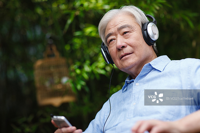 一个老年男人坐在椅子上戴着耳机图片素材