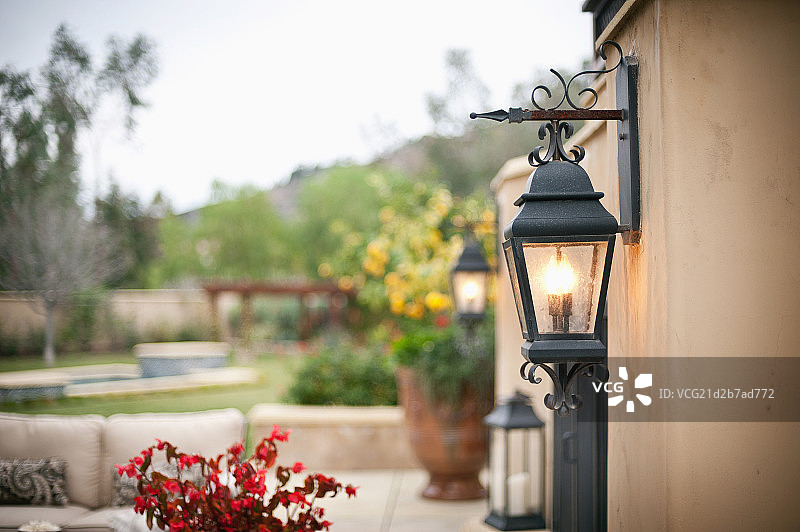 Lit lanterns on house wall with plants in the background,Rancho Sante Fe,USA图片素材