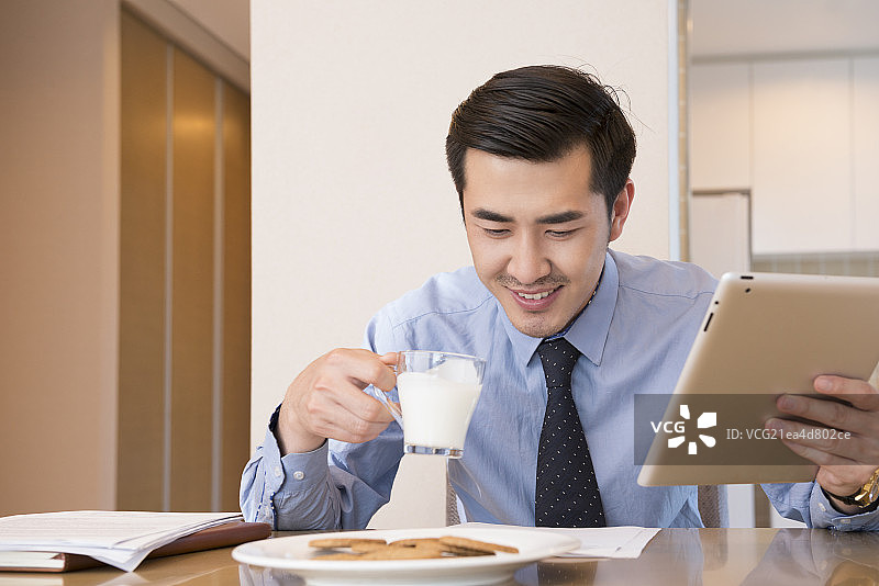 Young man using laptop at breakfast图片素材