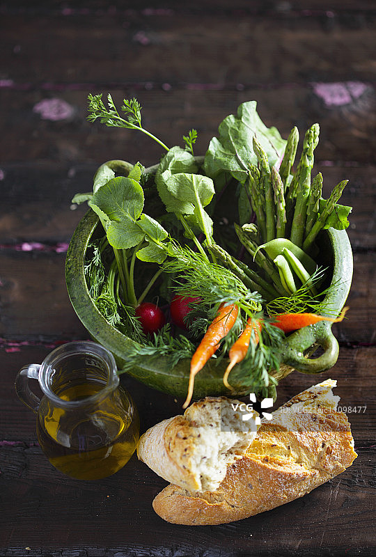 春天的蔬菜在一个绿色的罐子，白面包和一小罐橄榄油图片素材