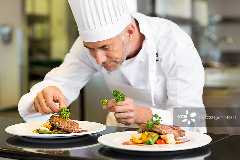 一个集中的男性厨师在厨房装饰食物的特写图片素材