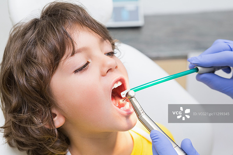 儿科牙医在牙科诊所的牙医椅上检查一个小男孩的牙齿图片素材