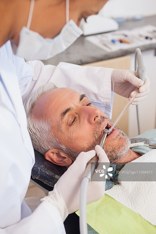 牙科医生在牙科诊所的牙医椅上检查病人的牙齿图片素材