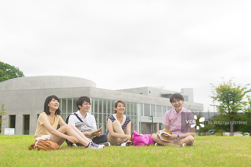 坐在草地上微笑的大学生图片素材