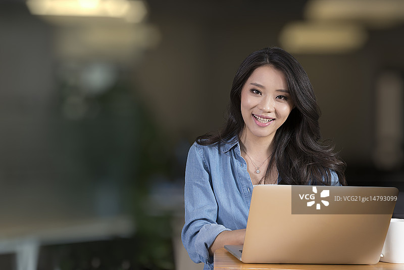 Creative businesswoman using laptop in break room图片素材