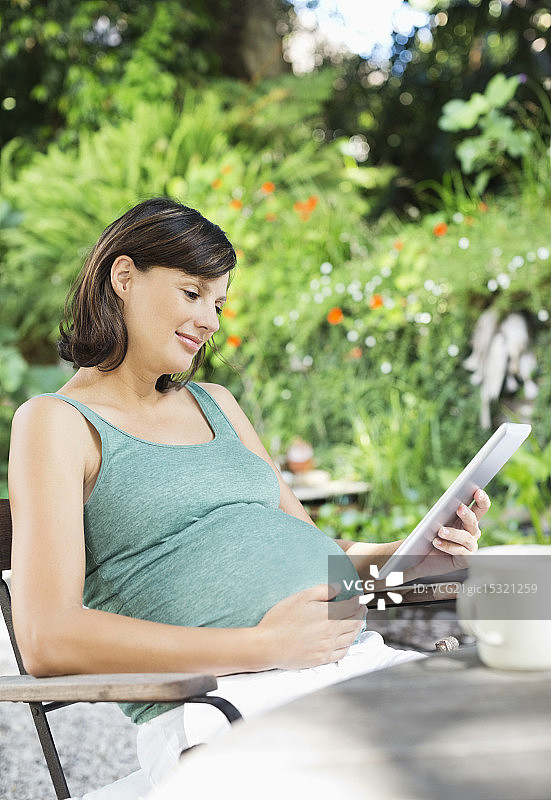 孕妇在户外使用平板电脑图片素材