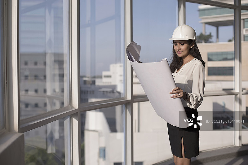 新加坡，女建筑师戴着安全帽看建筑计划图片素材