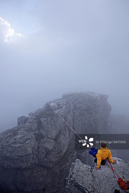 奥地利泰罗尔，一名男子坐在两座岩石之间的高压线前图片素材