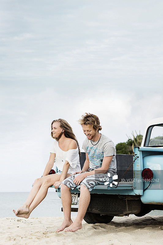 一对夫妇坐在沙滩上的卡车后挡板上图片素材
