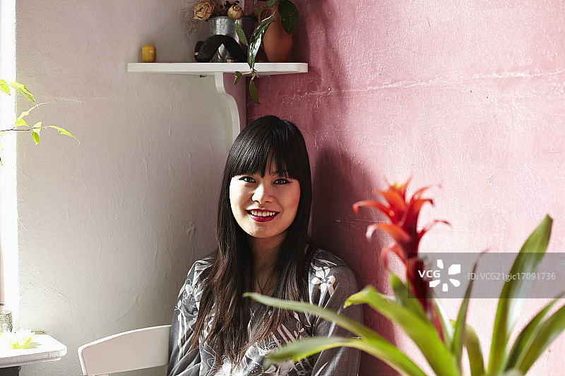 一个年轻的中国妇女坐在她的厨房微笑的肖像图片素材