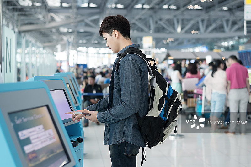 年轻的亚洲男子使用机场自助值机服务图片素材