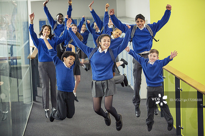 热情洋溢的高中生穿着校服，在学校走廊上微笑跳跃图片素材
