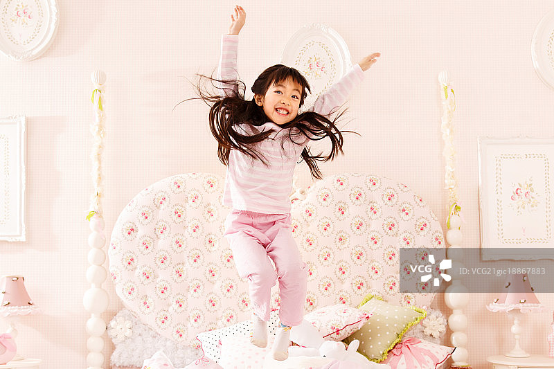 可爱的小女孩在床上跳跃图片素材