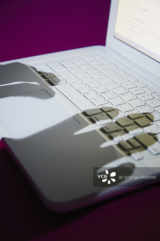 手提电脑键盘上的手的剪影图片素材
