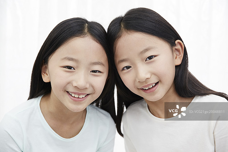 一对双胞胎姐妹对着镜头微笑图片素材