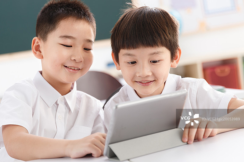两个小学生在使用平板电脑图片素材
