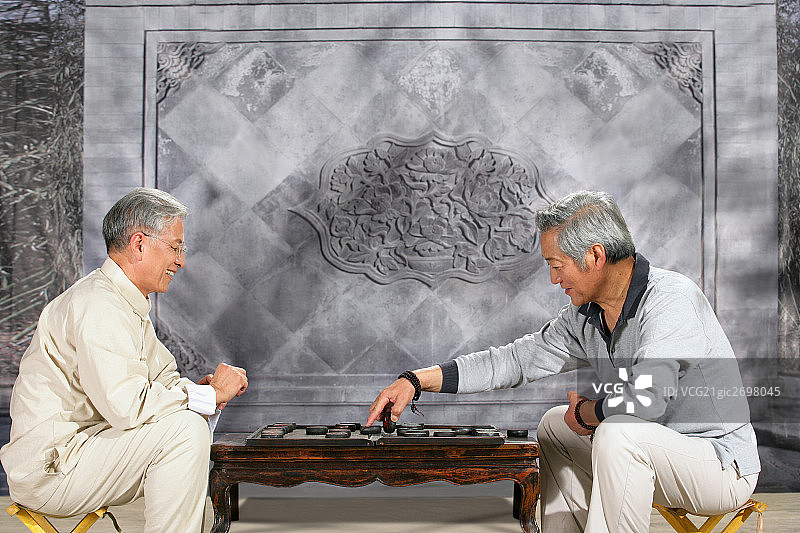 two oriental senior adults play chinese chess图片素材