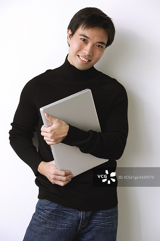 男人抱着笔记本电脑,笑了图片素材