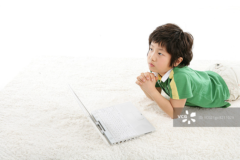 男孩(12-13岁)躺在地毯上，拿着笔记本电脑，俯瞰高处图片素材