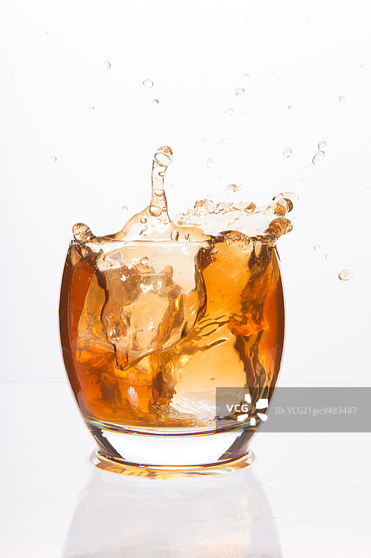 白色背景上有棕色酒精的平底玻璃杯图片素材