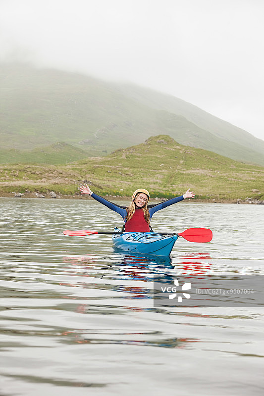 一名金发女子在湖中划着皮艇对着镜头欢呼图片素材