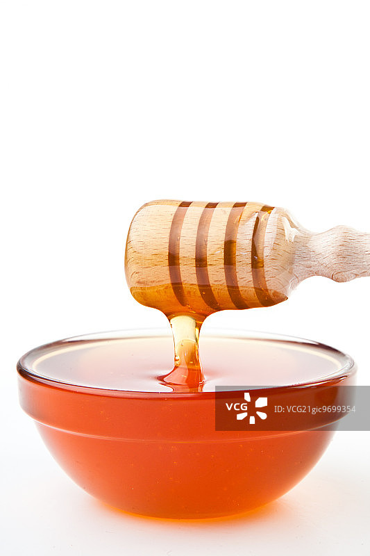 蜂蜜勺水平地在白色的背景下滴下一滴蜂蜜图片素材
