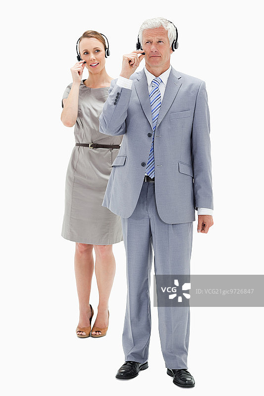 商人和一个女人在背景中说话戴着耳机对着白色的背景图片素材